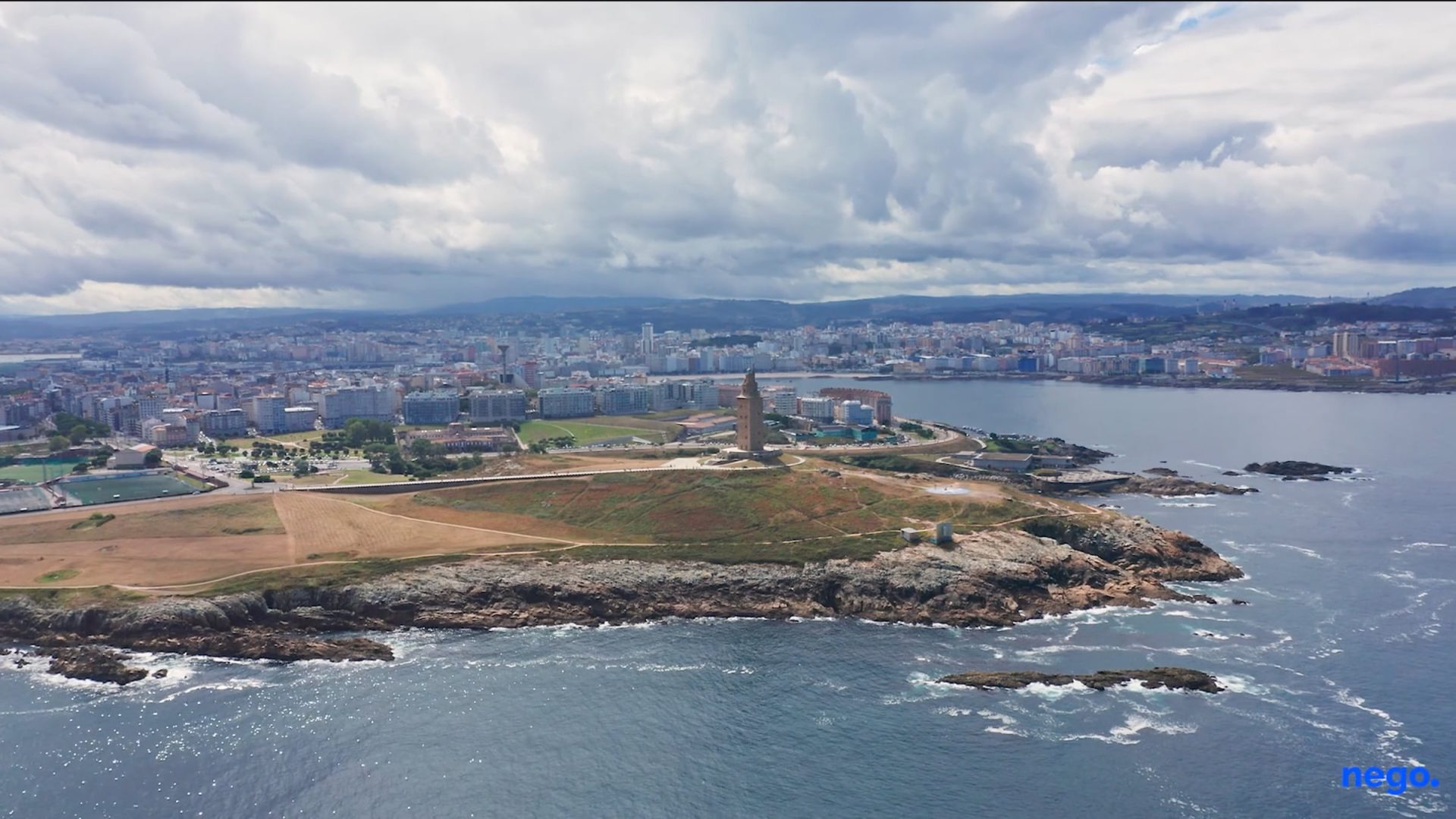 Vista aérea del faro de Hércules y la costa de A Coruña con la ciudad al fondo bajo un cielo nublado