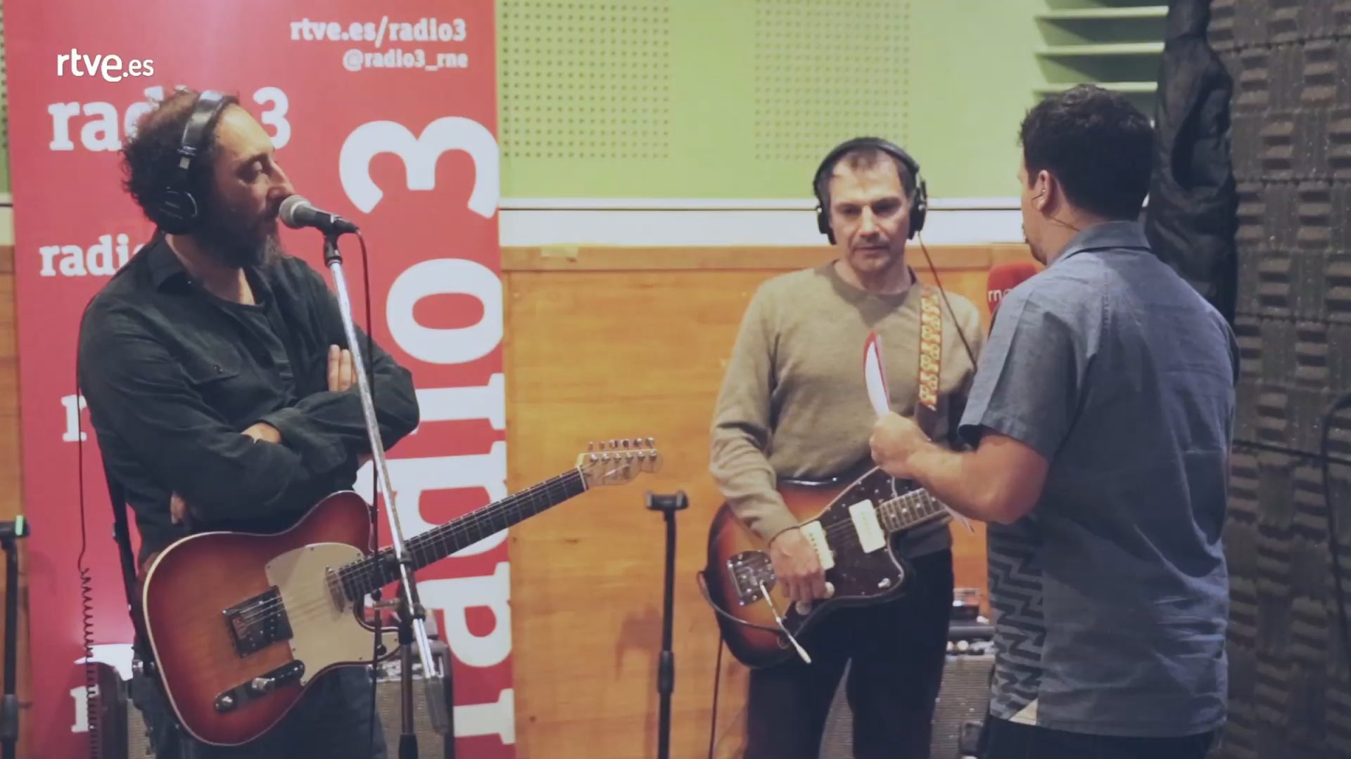 Técnicos y músicos en estudio de grabación radio3 con guitarras y micrófono
