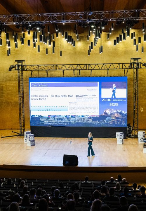Fotografía de congreso AEDE 2025 - Ponente femenina en escenario con pantalla de implantes dentales Alicante