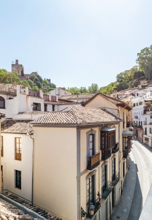 Fotografía de vistas desde balcón de hotel en el Albaicín - Calle típica de Granada con la Alhambra al fondo